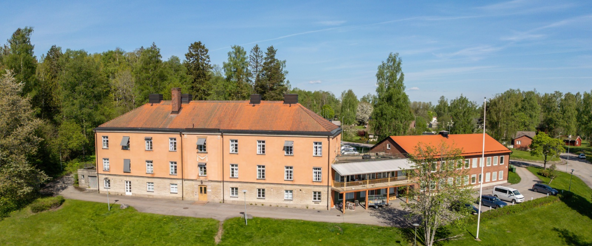 Bilden visar en fastighet i terrakottafärg, kallat Hasselhuset i Hallsberg